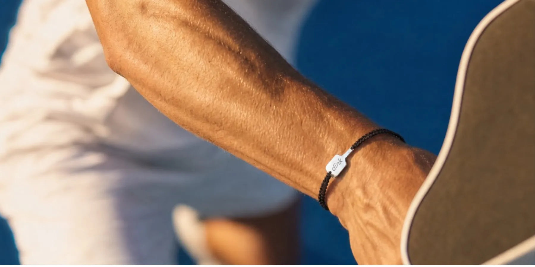 a close-up of a black bracelet with a white paddle charm on a man's wrist