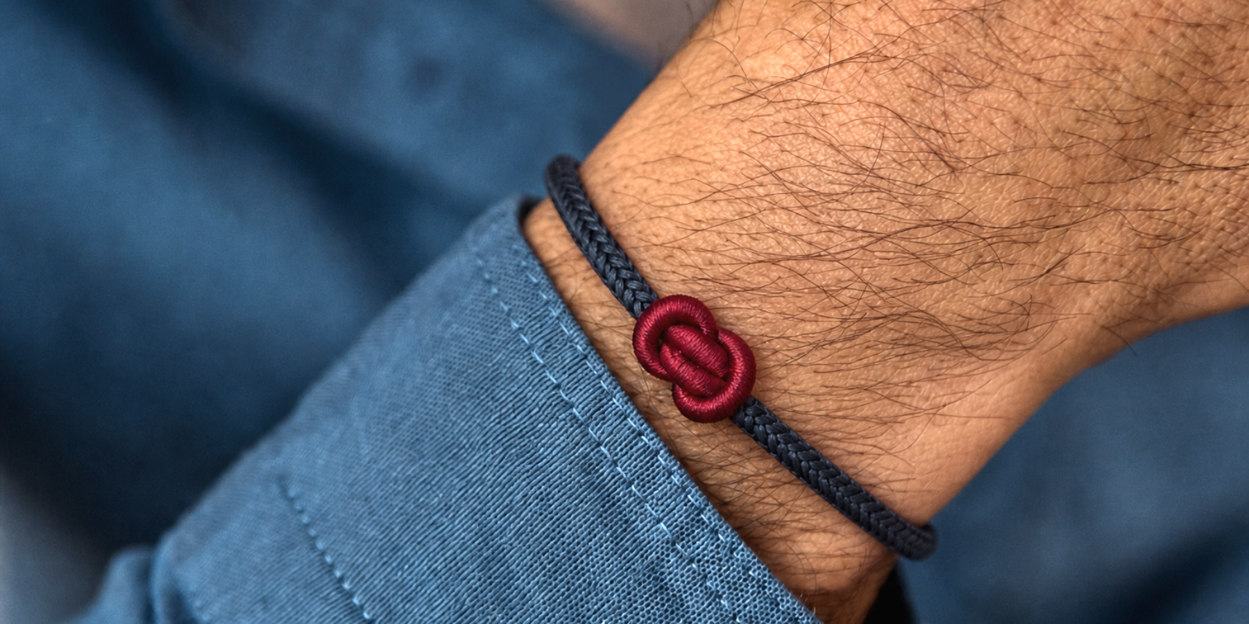 A black cord bracelet with a red yuanbao knot on a man's wrist