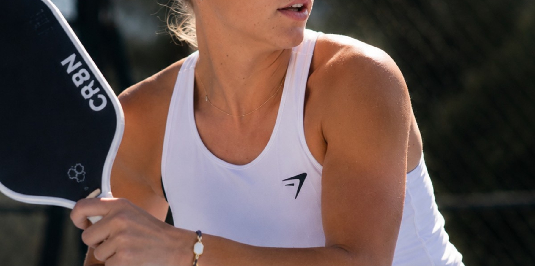woman holding a pickleball paddle and wearing a pickleball bracelet