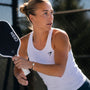 Woman playing pickleball holding a paddle on a court and wearing a pickleball bracelet