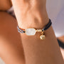 Close-up of a wrist wearing a pickleball bracelet with a gold charm on a blurred background