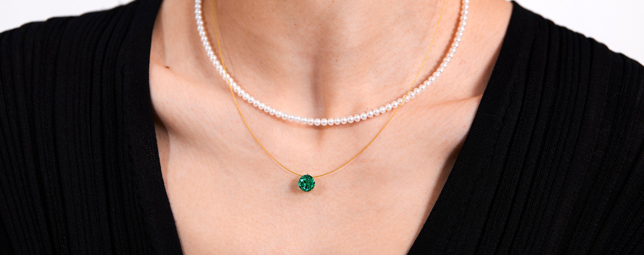Pearl necklace, gold nylon necklace with a green gemstone pendant on a black background