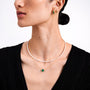 Woman wearing a pearl necklace, emerald necklace and green emerald earrings on a white background