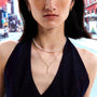 Woman wearing a pearl necklace and gold bar necklace in an urban setting