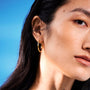 Close-up of a person wearing minimal gold hoop earrings