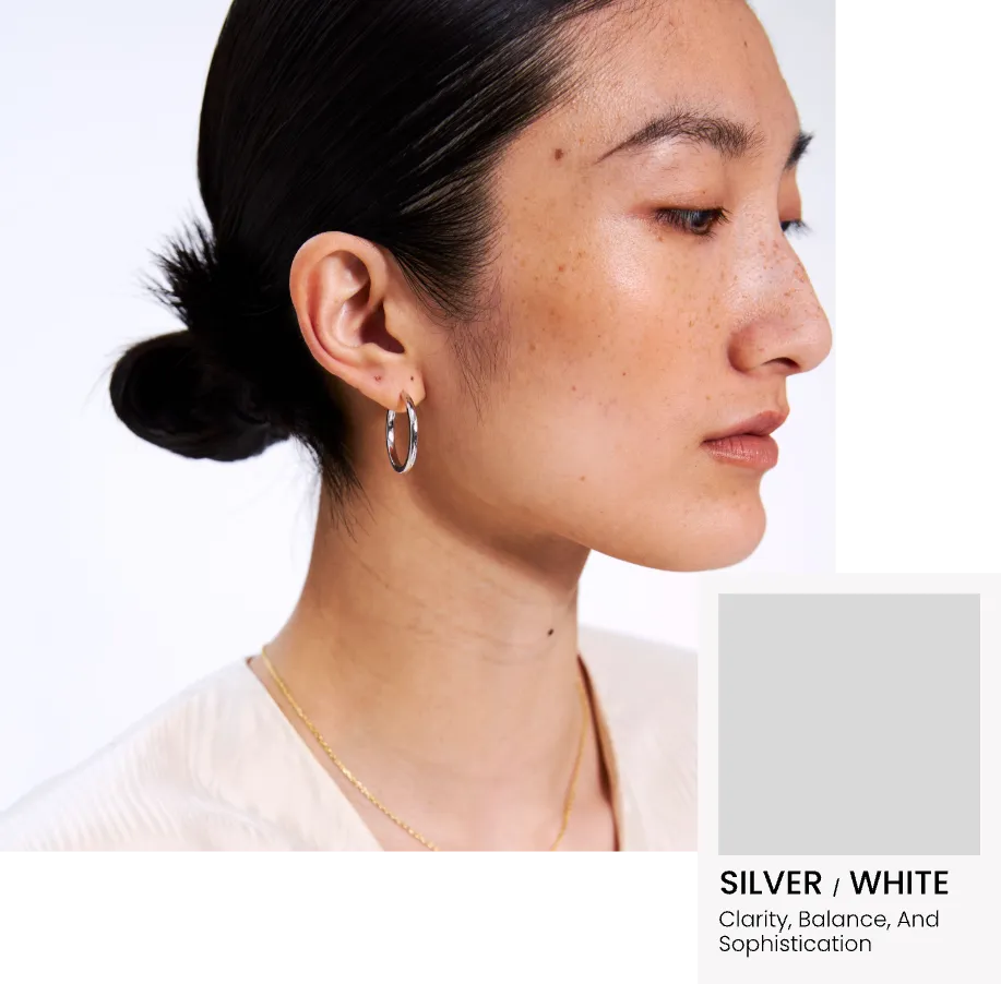 Close-up of a person wearing Glint & Luck's silver earring with a neutral background