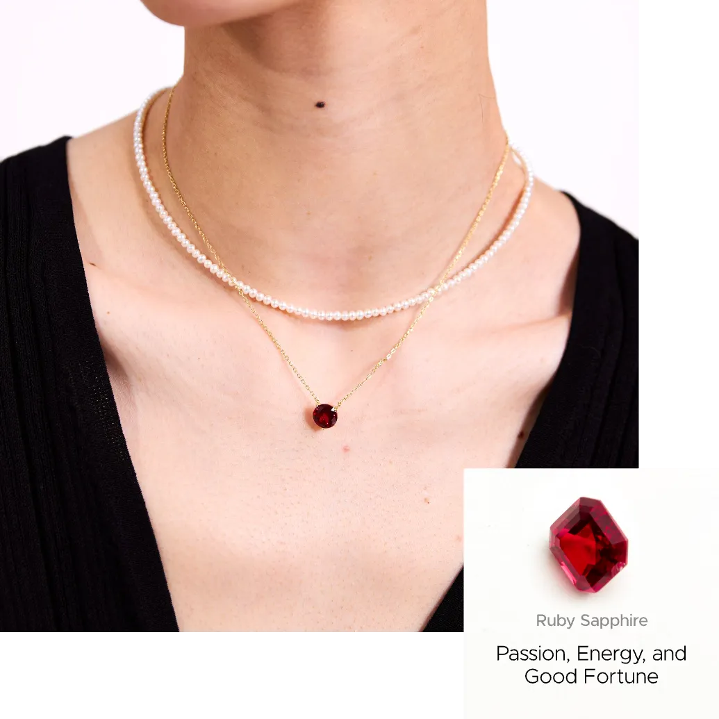 Gold necklace with a red gemstone pendant worn by a person, with an inset showing the gemstone.