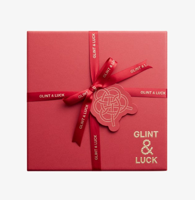 Red gift box with a bow and 'GLINT & LUCK' branding on a white background