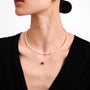 Woman wearing a pearl necklace and a wire necklace with ruby pendant