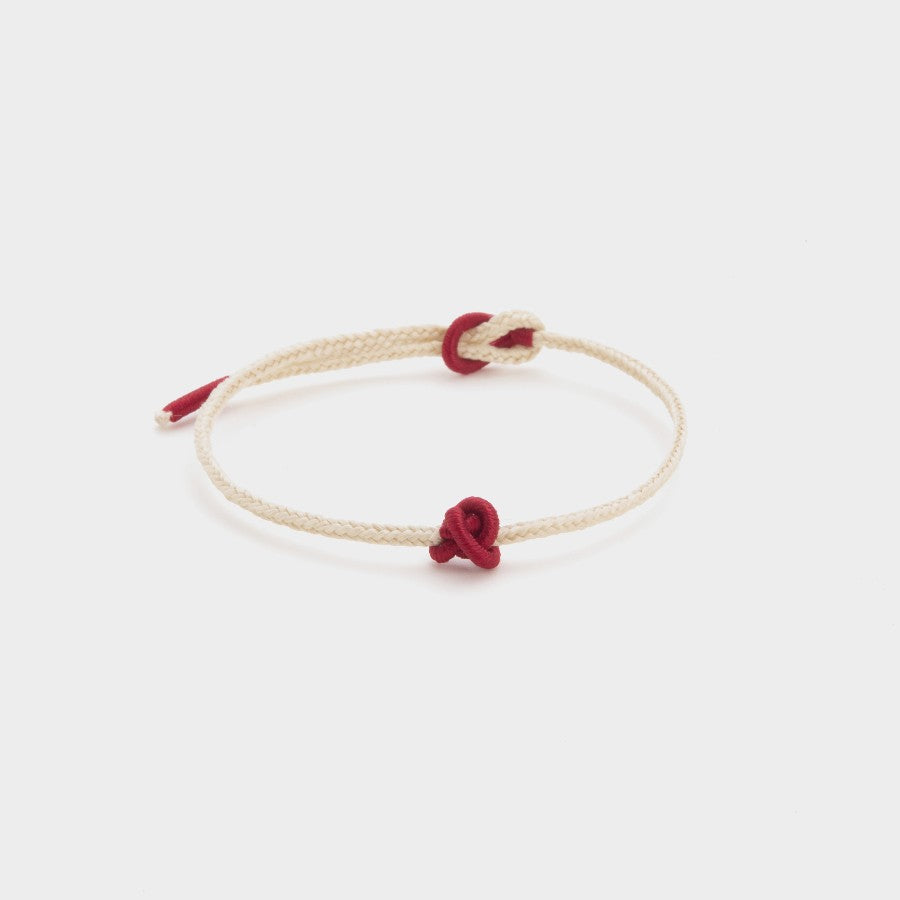 white string bracelet with a red union knot