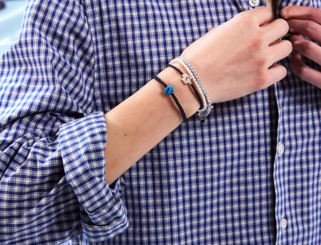Person wearing multiple bracelets on a blue and white checkered shirt