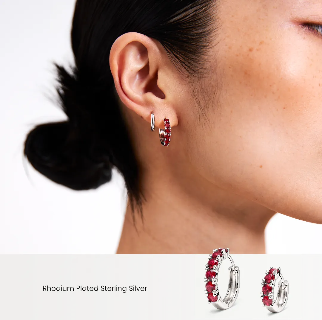 Close-up of a woman wearing red hoop earrings with a white background.