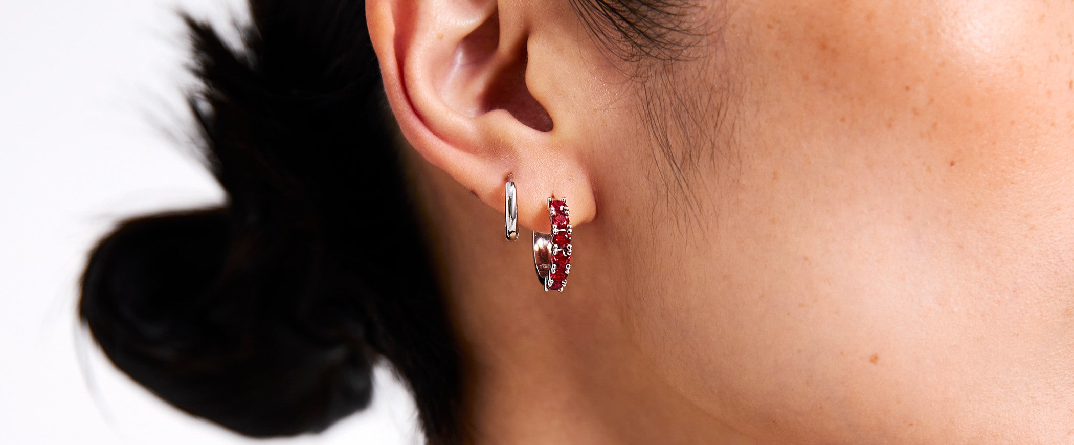 Close-up of a person wearing hoop earrings with a blurred background