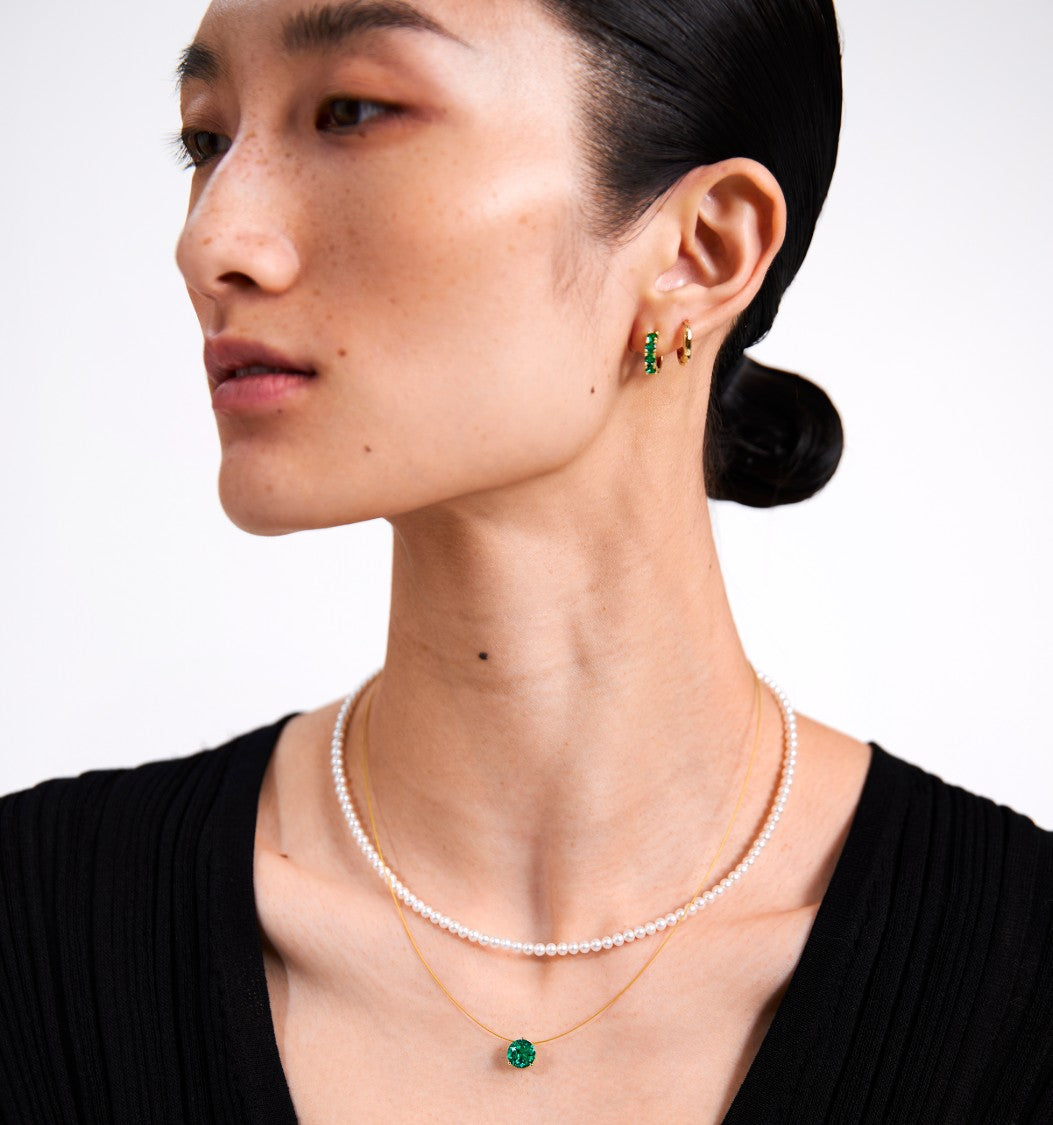 Woman wearing Glint & Luck pearl necklace, earrings, and floating glint green necklacce