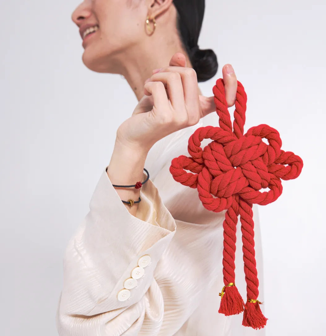 Person holding a red chinese knot with a plain background