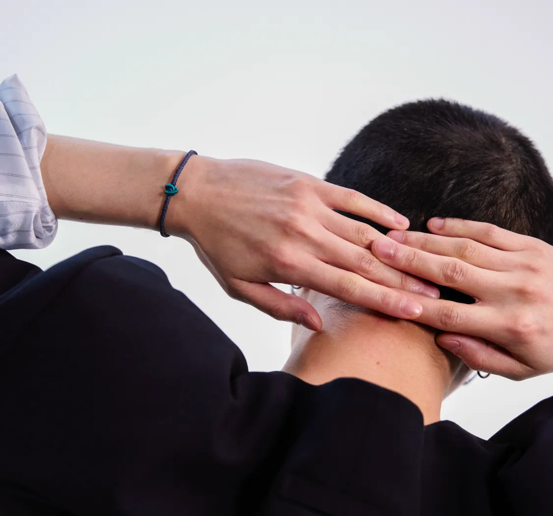 person holding his head with both hands and wearing a black string bracelet