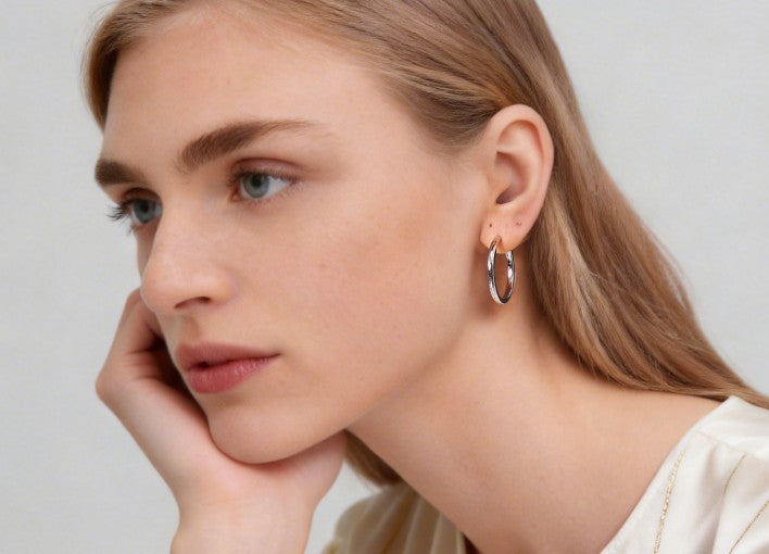 Close-up of a woman wearing a silver hoop earring against a neutral background