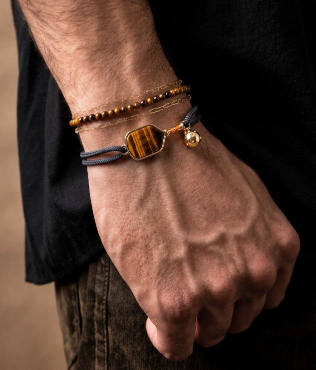 Close-up of a wrist wearing a pickleball bracelet and a beaded bracelet with a dark background