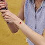 person wearing a white string bracelet with a red yuanbao knot