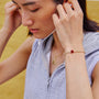 person wearing a white string bracelet with a red knot