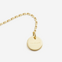 Gold necklace with a round plate on a white background