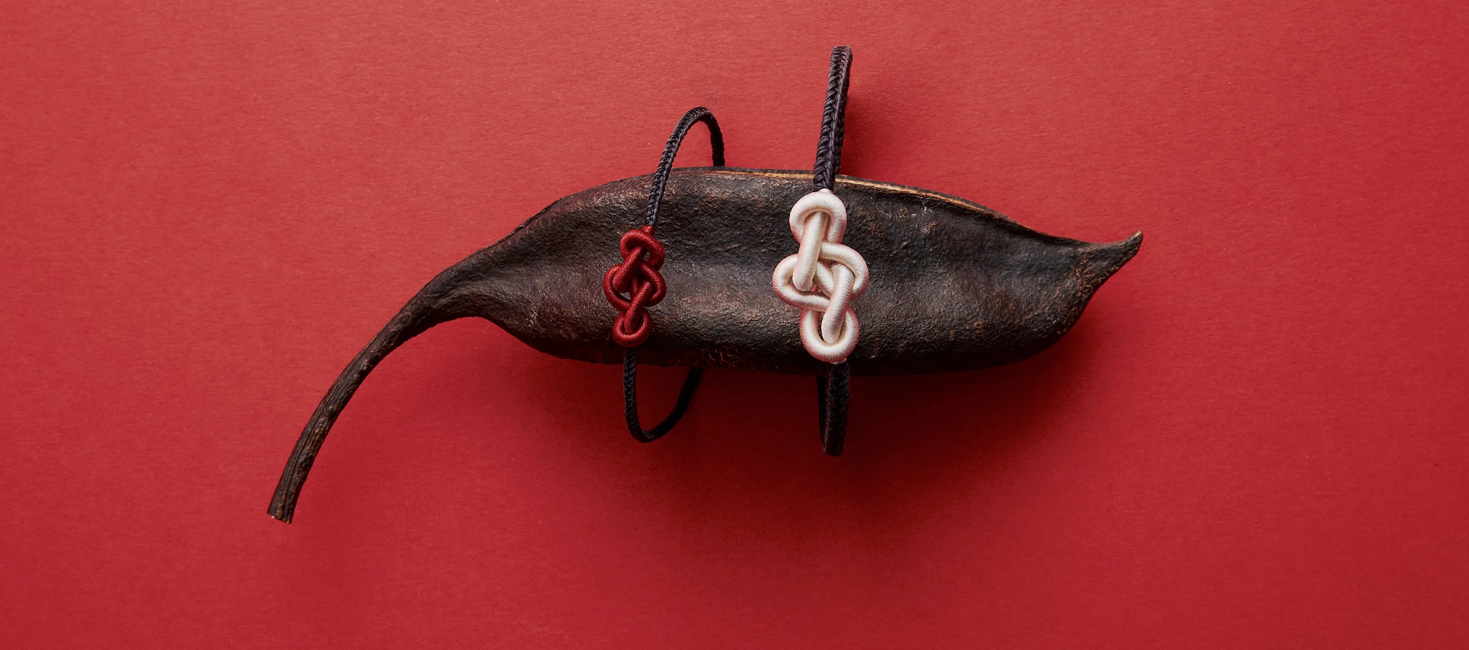 Red and white ruyi knot bracelets on a decorative leaf