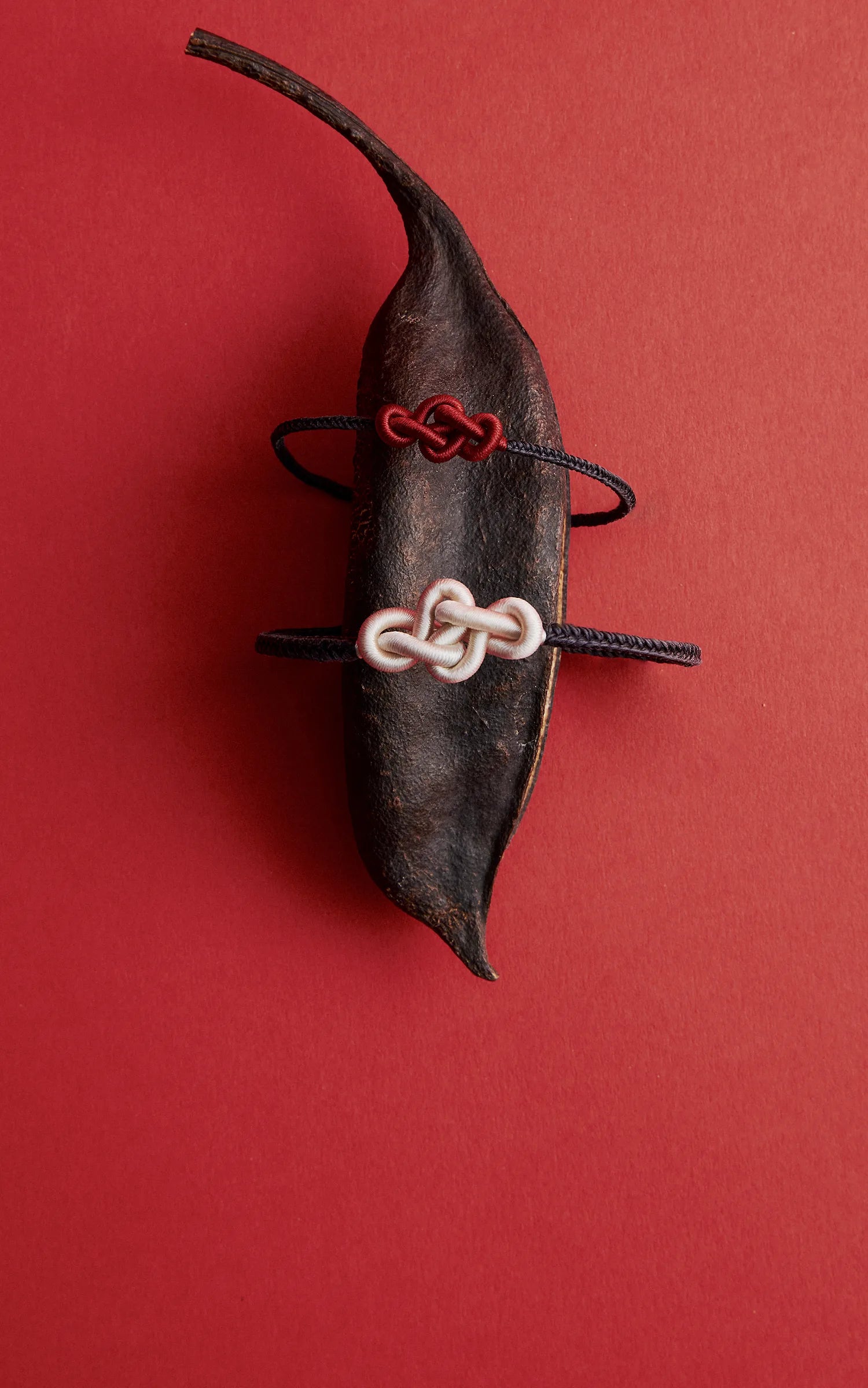 Red and white ruyi knot bracelets on a decorative leaf