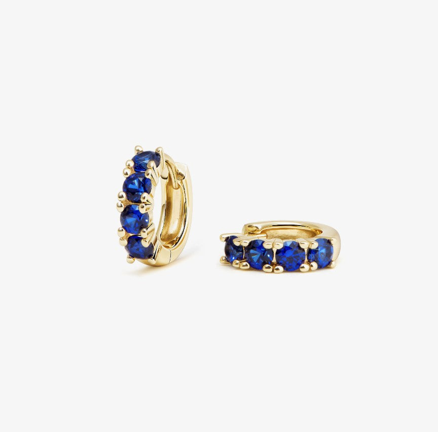 Gold hoop earrings with blue sapphire on a white background