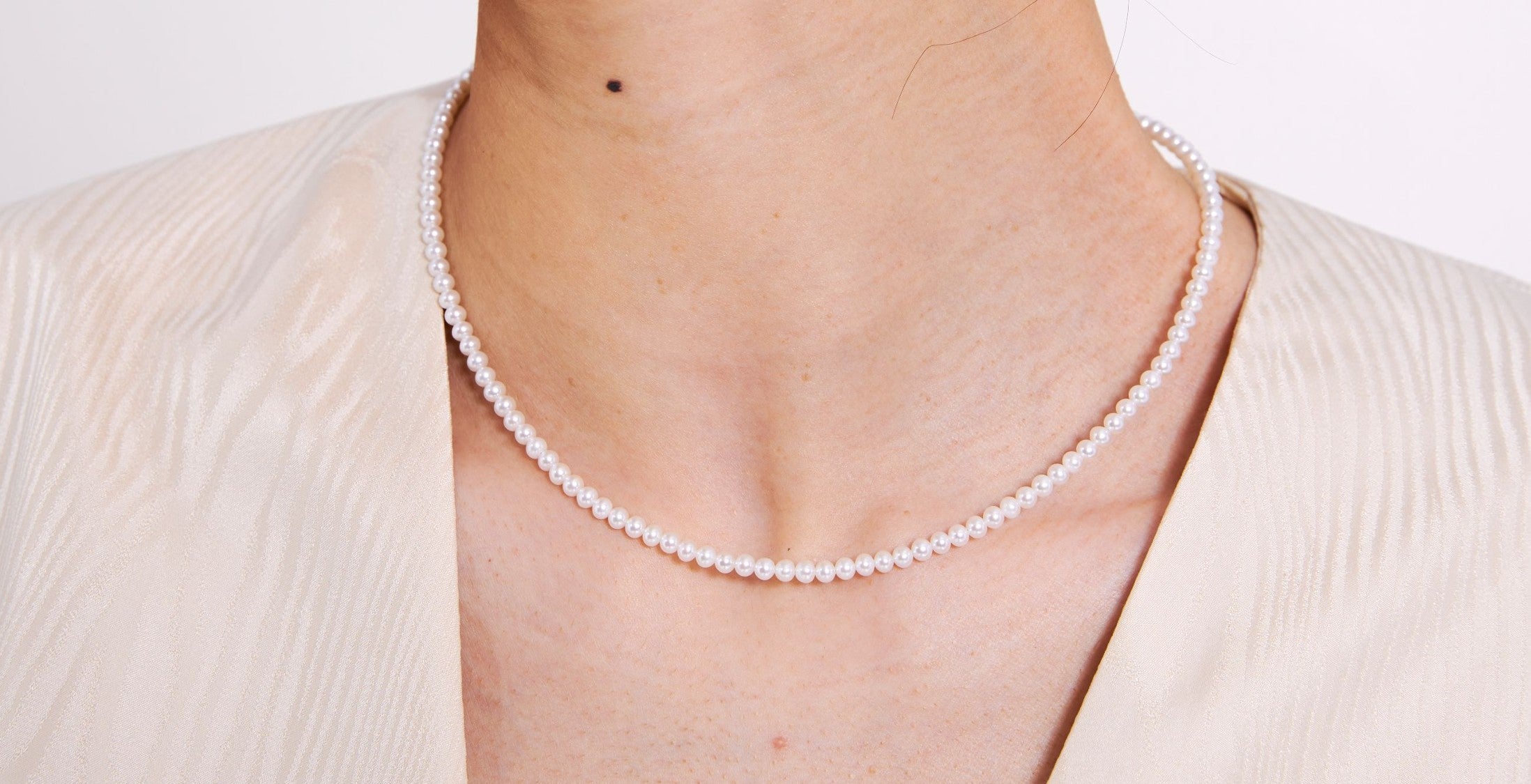 Glint & Luck pearl necklace worn by a person on a plain background