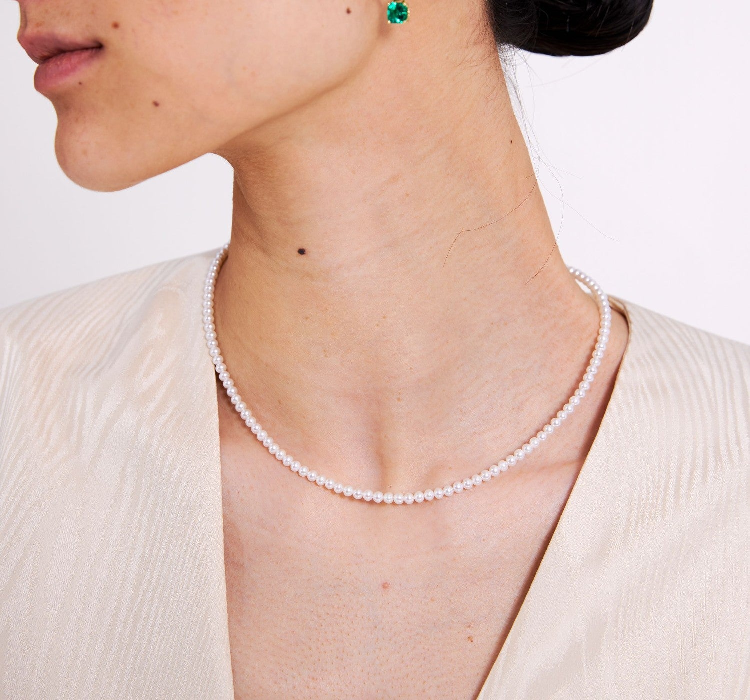 Pearl necklace worn by a person with a plain background