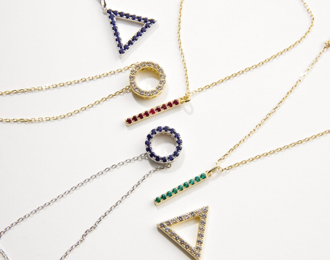 Collection of gold necklaces with various geometric pendants on a white background